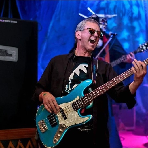 Chris Röhrl spielt seinen türkisfarbenen Jazz Bass live auf der Bühne, blaues und violettes Bühnenlicht